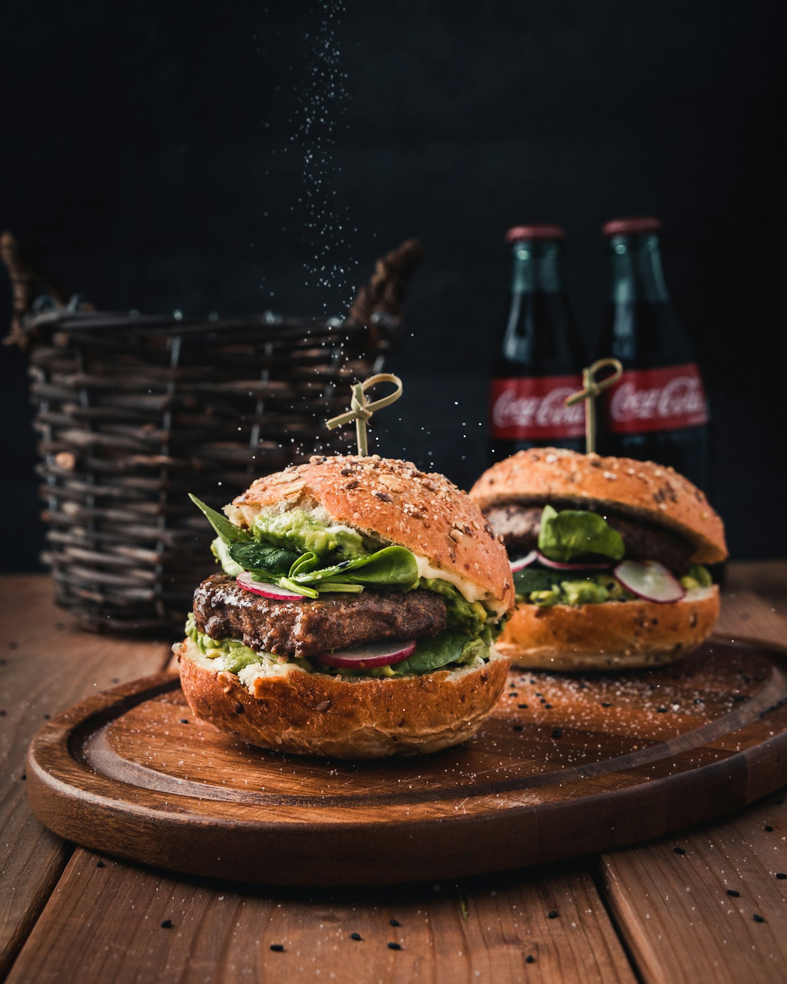 Dois hambúrgueres em ambiente rústico com refrigerante ao fundo